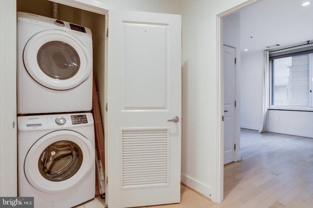 washroom with baseboards, light wood-style floors, laundry area, and stacked washer / dryer