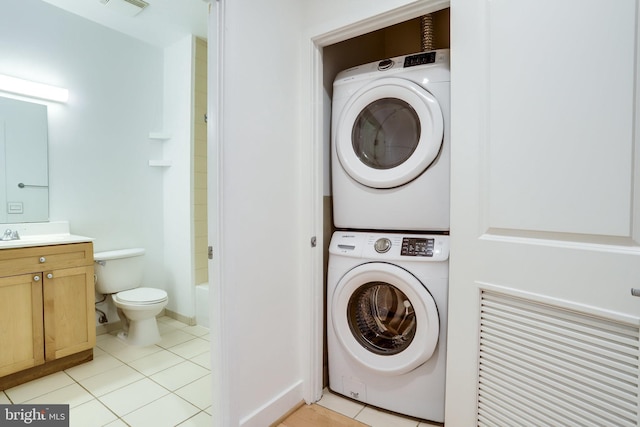 laundry area with light tile patterned floors, baseboards, visible vents, laundry area, and stacked washer / dryer