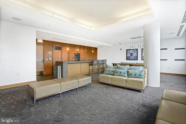 living area with baseboards, a tray ceiling, and dark colored carpet