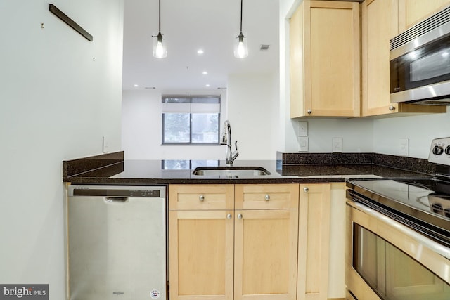 kitchen featuring light brown cabinetry, stainless steel appliances, and a sink