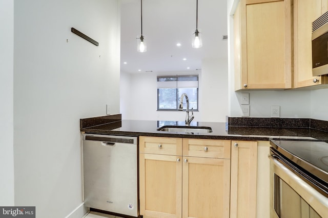 kitchen featuring dark stone countertops, a sink, light brown cabinetry, stainless steel appliances, and decorative light fixtures