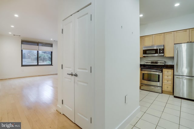 kitchen featuring dark countertops, light brown cabinets, baseboards, recessed lighting, and stainless steel appliances