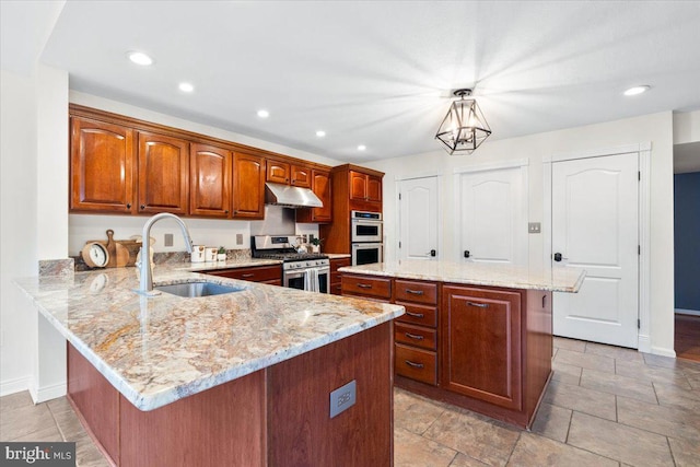 kitchen with under cabinet range hood, a peninsula, a kitchen island, a sink, and appliances with stainless steel finishes