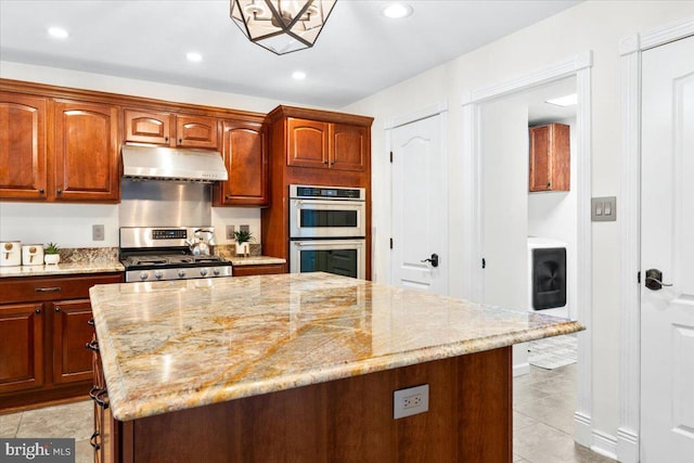 kitchen featuring stainless steel appliances, under cabinet range hood, and light stone counters