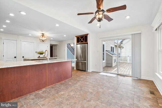 kitchen featuring recessed lighting, a sink, visible vents, freestanding refrigerator, and light stone countertops