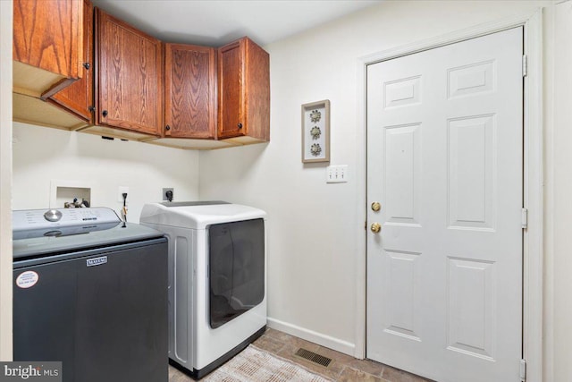 laundry area with cabinet space, washing machine and dryer, visible vents, and baseboards