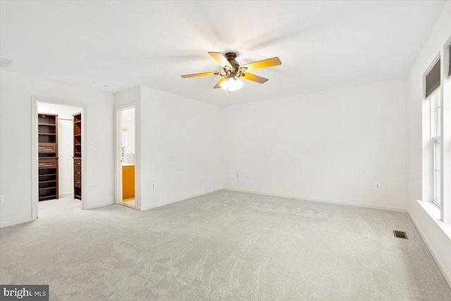 unfurnished room with light carpet, a ceiling fan, visible vents, and a healthy amount of sunlight