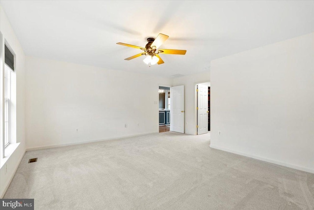 carpeted empty room featuring visible vents, baseboards, and a ceiling fan