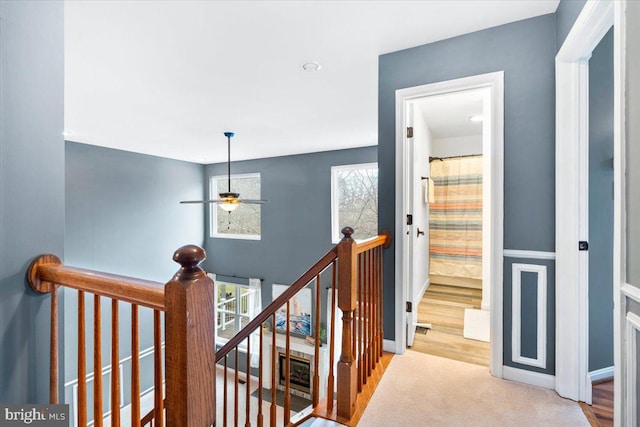 hallway with carpet floors, baseboards, and an upstairs landing