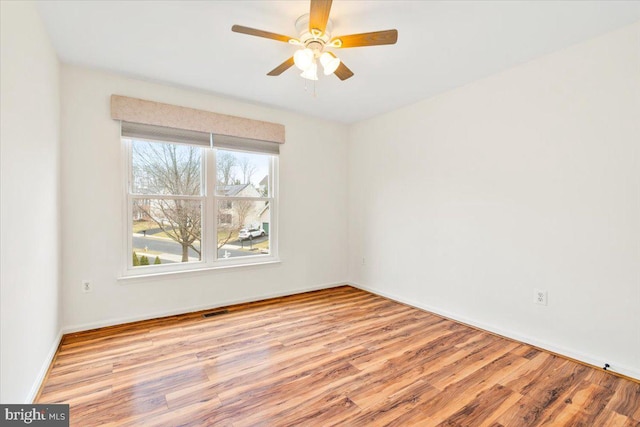 spare room with visible vents, ceiling fan, baseboards, and wood finished floors