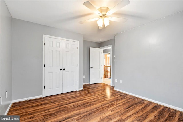 unfurnished bedroom featuring a closet, wood finished floors, a ceiling fan, and baseboards