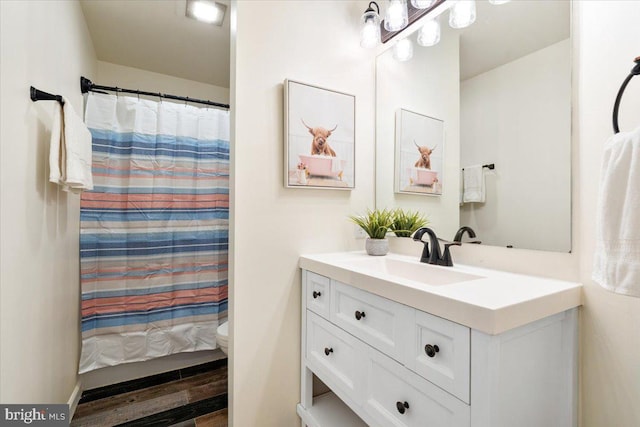 full bathroom featuring toilet, curtained shower, wood finished floors, and vanity