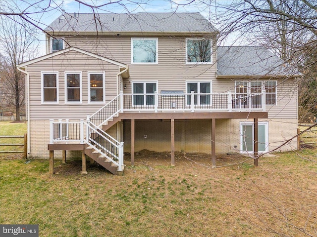 rear view of property with a deck, brick siding, fence, stairs, and a lawn