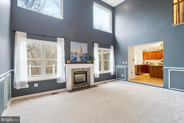 unfurnished living room with light carpet, plenty of natural light, a fireplace, and visible vents