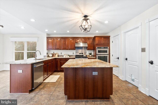 kitchen with under cabinet range hood, a peninsula, a sink, appliances with stainless steel finishes, and a center island