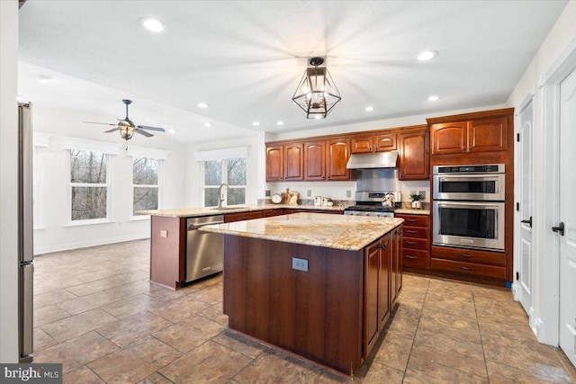 kitchen featuring a kitchen island, appliances with stainless steel finishes, a peninsula, under cabinet range hood, and a sink