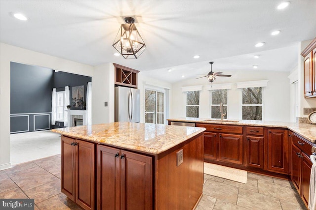 kitchen with a center island, stainless steel appliances, vaulted ceiling, a sink, and a peninsula