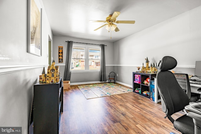 office space featuring a ceiling fan, baseboards, and wood finished floors