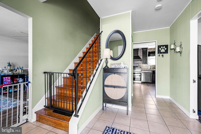 stairway with ornamental molding, baseboards, and tile patterned floors