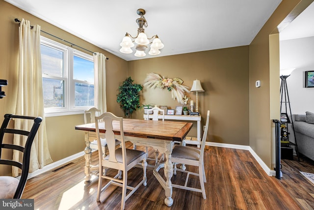 dining room featuring visible vents, a notable chandelier, baseboards, and wood finished floors