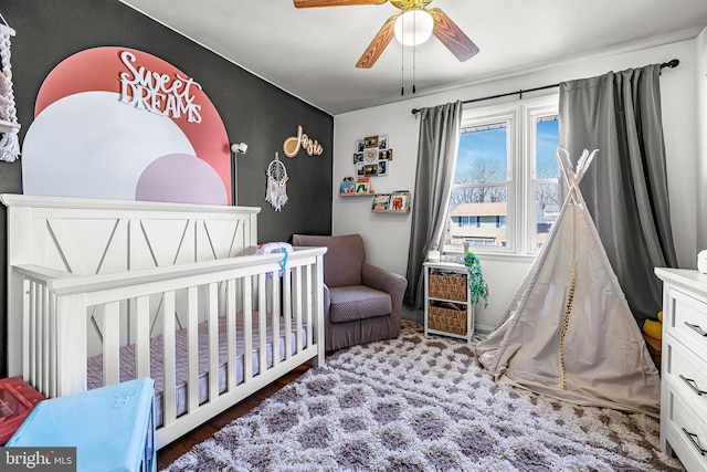 bedroom featuring ceiling fan and a crib