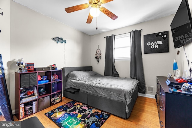 bedroom featuring a ceiling fan, visible vents, baseboards, and wood finished floors