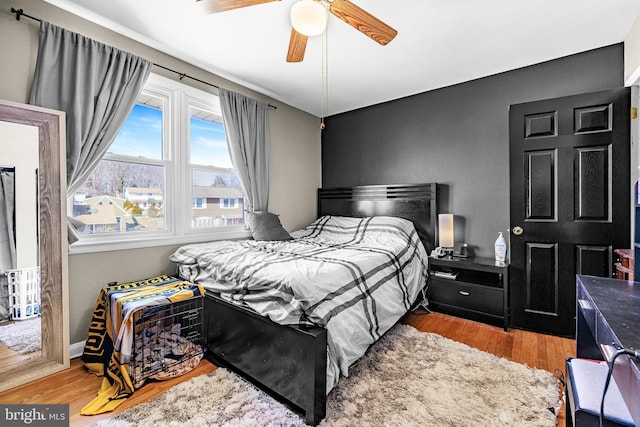 bedroom with a ceiling fan, baseboards, and wood finished floors