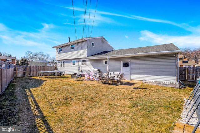 rear view of property with a trampoline, a fenced backyard, a yard, and a patio