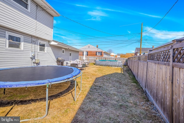 view of yard featuring a fenced backyard, a trampoline, and a fenced in pool