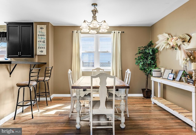 dining space featuring an inviting chandelier, baseboards, and wood finished floors