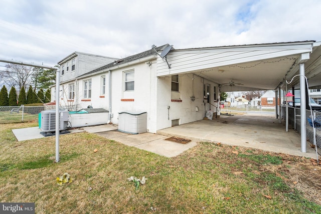 view of side of home featuring central air condition unit, fence, a lawn, and stucco siding