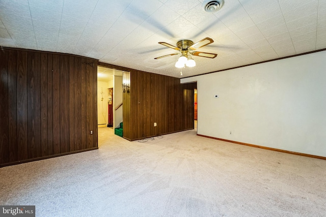 unfurnished room with carpet floors, visible vents, wood walls, and ornamental molding