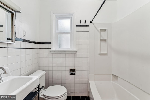 bathroom with toilet, shower / bath combination, tile walls, and a sink