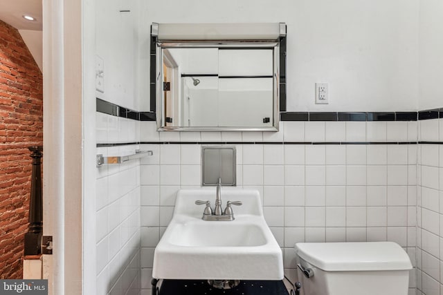 half bathroom with a sink, toilet, and tile walls