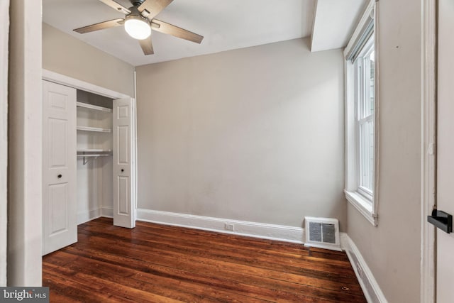 unfurnished bedroom with baseboards, multiple windows, visible vents, and dark wood-style flooring