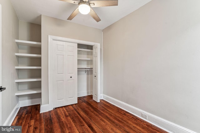 unfurnished bedroom with ceiling fan, a closet, dark wood finished floors, and baseboards