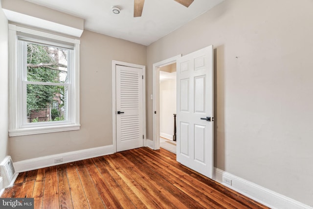 unfurnished bedroom with visible vents, multiple windows, hardwood / wood-style flooring, and baseboards