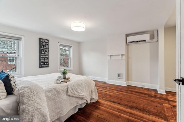 bedroom featuring dark wood-style floors, visible vents, baseboards, and a wall mounted air conditioner