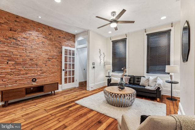 living room featuring ceiling fan, hardwood / wood-style floors, and brick wall