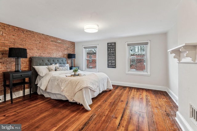 bedroom with hardwood / wood-style flooring, brick wall, and baseboards