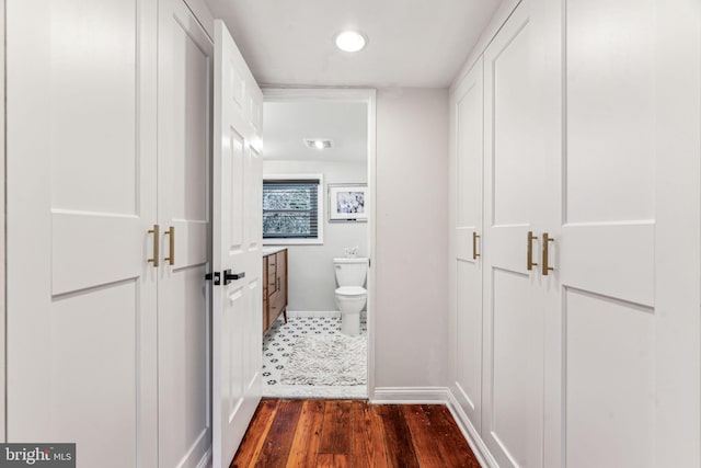 hall featuring dark wood-style floors, visible vents, and baseboards