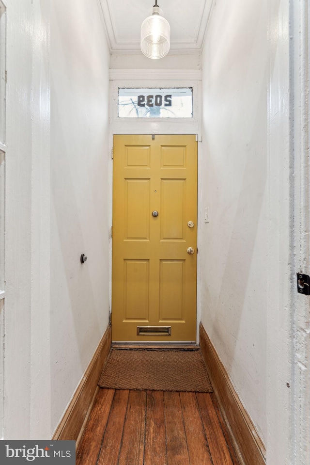 doorway with crown molding, baseboards, and hardwood / wood-style flooring