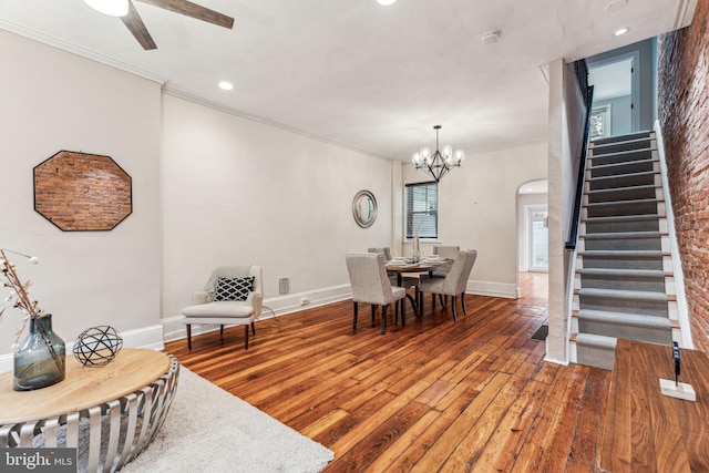 dining area featuring baseboards, stairway, ornamental molding, hardwood / wood-style floors, and ceiling fan with notable chandelier