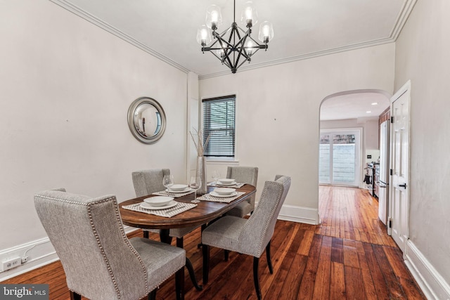 dining area with ornamental molding, arched walkways, wood-type flooring, and baseboards