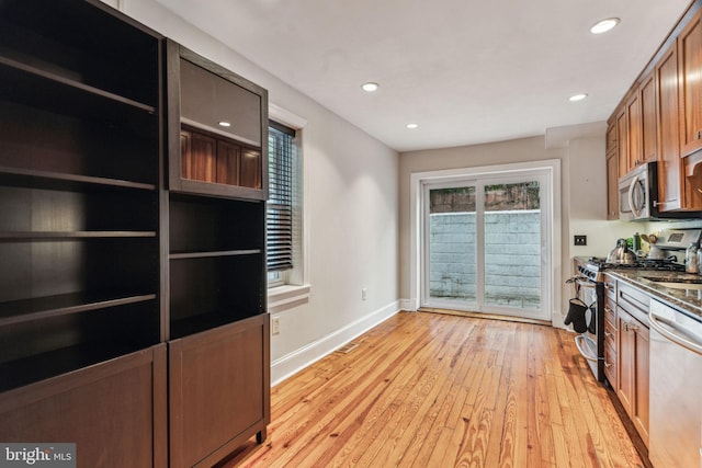 kitchen with brown cabinets, recessed lighting, light wood-style flooring, appliances with stainless steel finishes, and baseboards