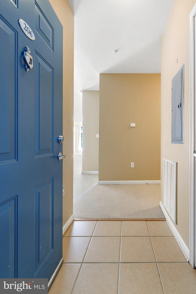 carpeted foyer entrance with baseboards, tile patterned floors, visible vents, and electric panel