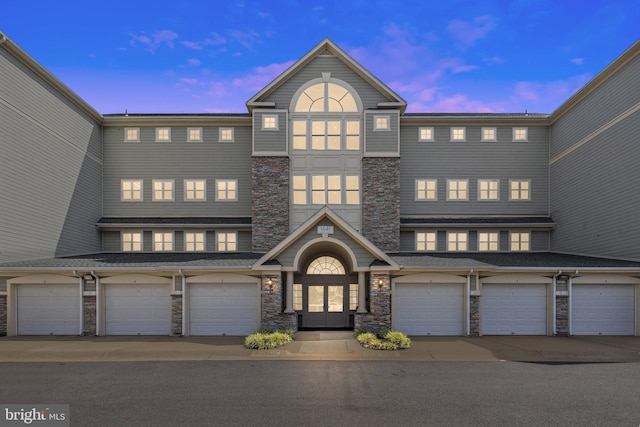 multi unit property with a garage and stone siding