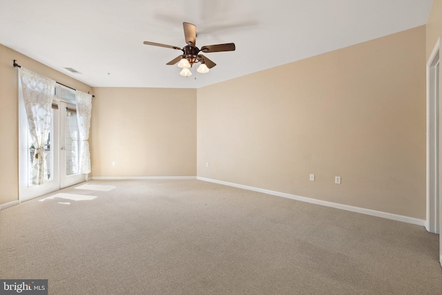 carpeted empty room featuring ceiling fan, visible vents, and baseboards