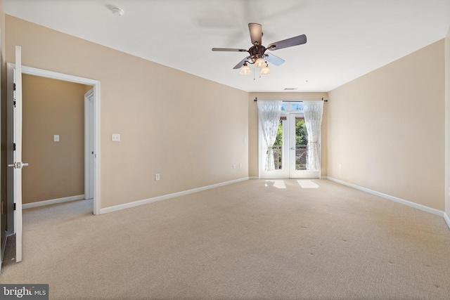 empty room featuring a ceiling fan, light colored carpet, and baseboards