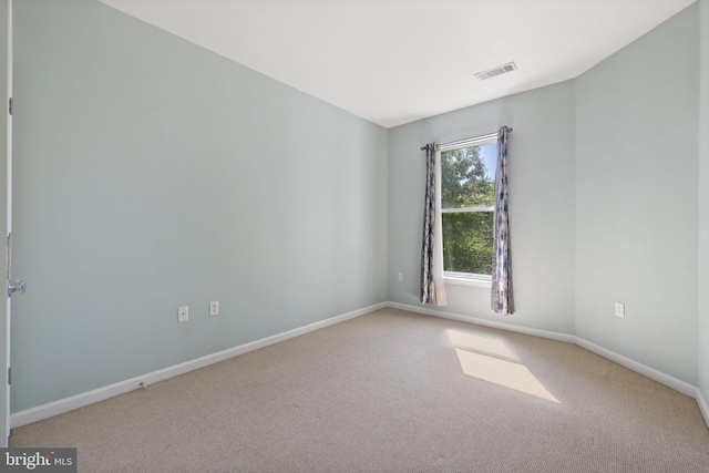 unfurnished room with carpet, visible vents, and baseboards